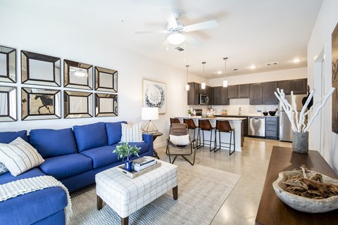 a living room and kitchen with a blue couch and a coffee table